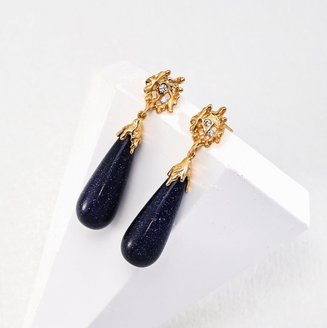 A pair of blue earrings with gold vermeil accents and zircon stones, displayed against a white background.